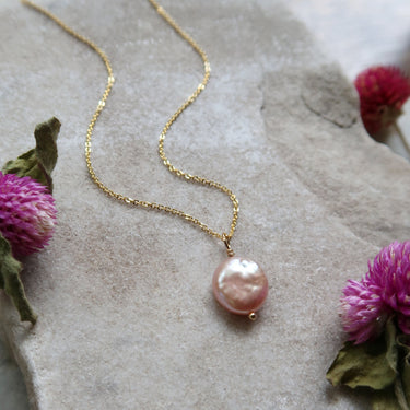 A beautiful pink coin pearl pendant carefully wire wrapped with 14k gold fill wire and strung on an 18-inch gold fill chain.