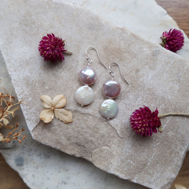 Earrings feature one pink coin pearl and one white coin pearl, dangling gracefully from sterling silver earring hooks.